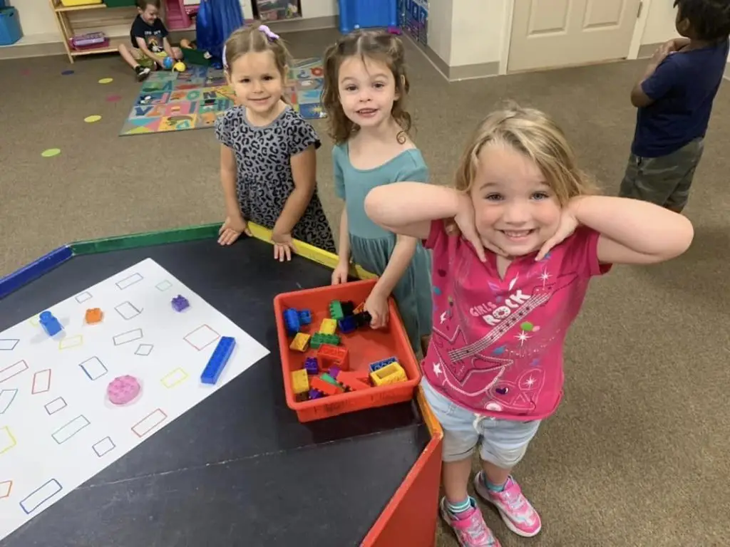 3 kids smiling in K2 day care classroom